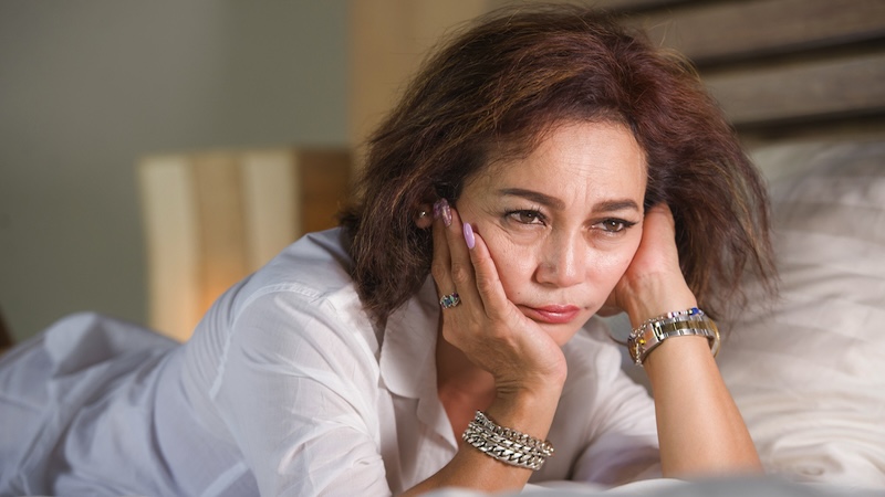 Woman sad in bed because of old insecurities.