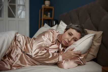Woman worried in bed experiencing poor sleep.