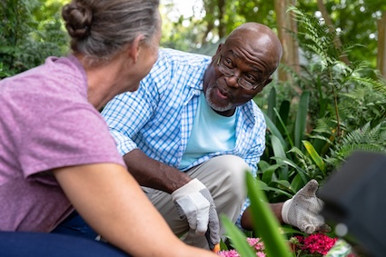 two seniors gardening together and smiling, to accentuate the positive. By Wavebreakmedia