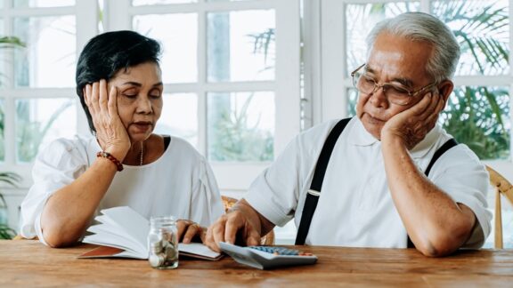 Senior couple crunching numbers on a calculator figuring out how to save money.