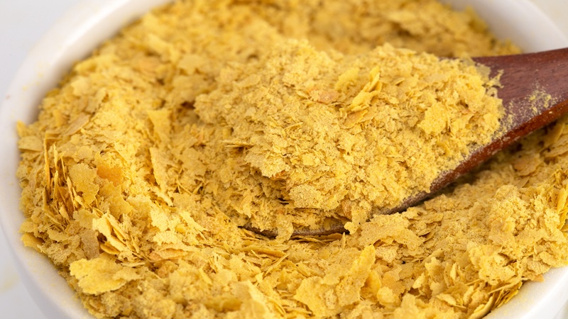 Nutritional yeast in a bowl and a wooden spoon