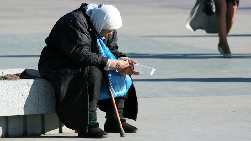 Senior homelessness: a senior woman begs on a city street