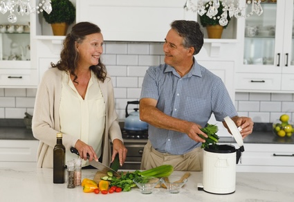 A couple at home preparing dinner and doing at-home composting. By Wavebreakmedia Ltd 