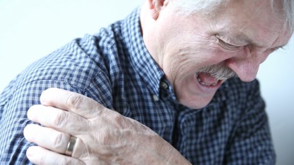 Man holding his shoulder and grimacing in pain after having a dislocated shoulder
