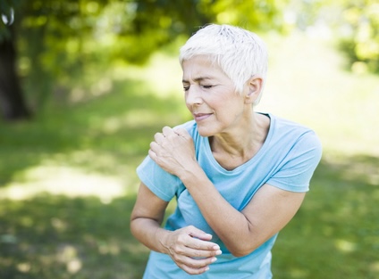 A woman experiencing shoulder pain, from dislocated shoulder, rotator cuff issues, or other problems. By Goran Bogicevic