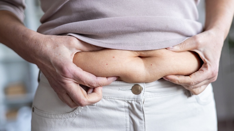 A woman pinching her belly fat.