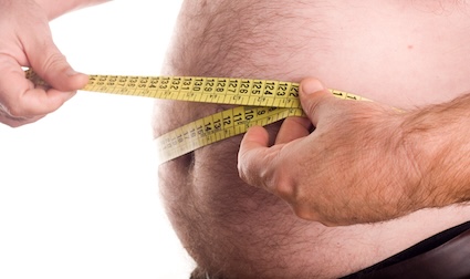 A man measuring his horrible excessive belly fat due to metabolic syndrome