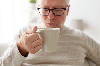 Man drinking a hot beverage to stay warm and help manage chronic conditions in cold weather,