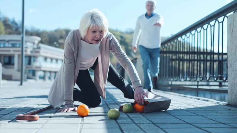 A senior woman who dropped her groceries on the ground. Some seniors like her start to get clumsy when aging.