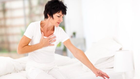 A woman clutching her heart because of chest pain.