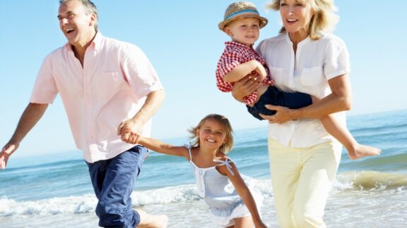 Couple on a beach with their grandkids.