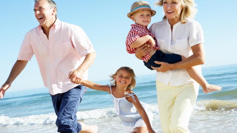 Couple on a beach with their grandkids.