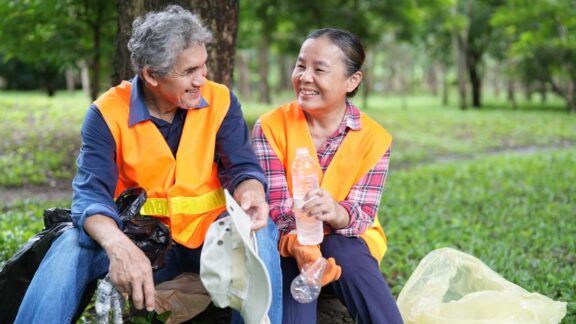 A retired couple taking a break from volunteer trash pick up at a park, one way of finding purpose after retirement