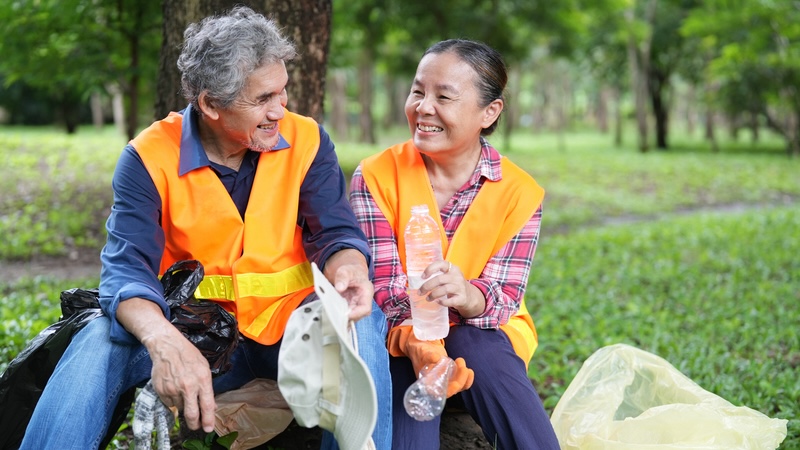 A retired couple taking a break from volunteer trash pick up at a park, one way of finding purpose after retirement