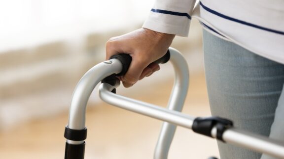 Woman with walker, might wonder if it's time to ditch the mobility aids. Fizkes.