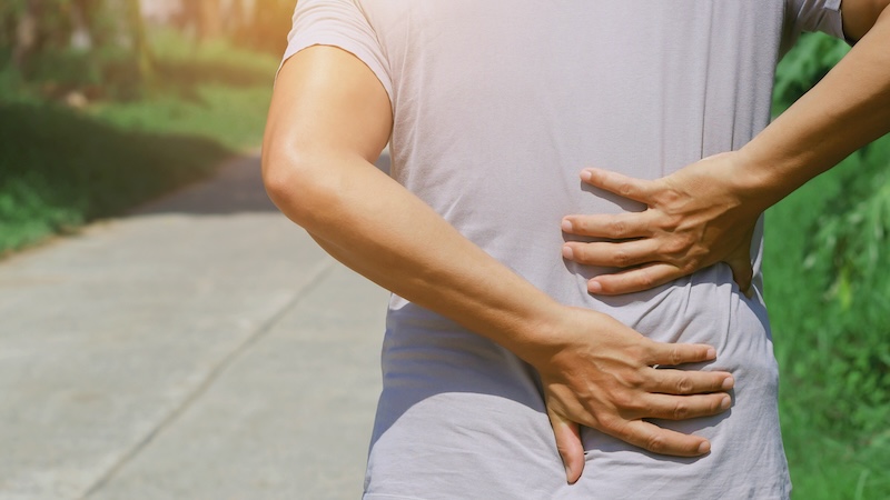 Senior holding her back needing to dispel myths about back pain.