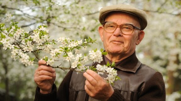 An elderly man stopping to smell the flowers, as he knows what it means to age well. Nejron