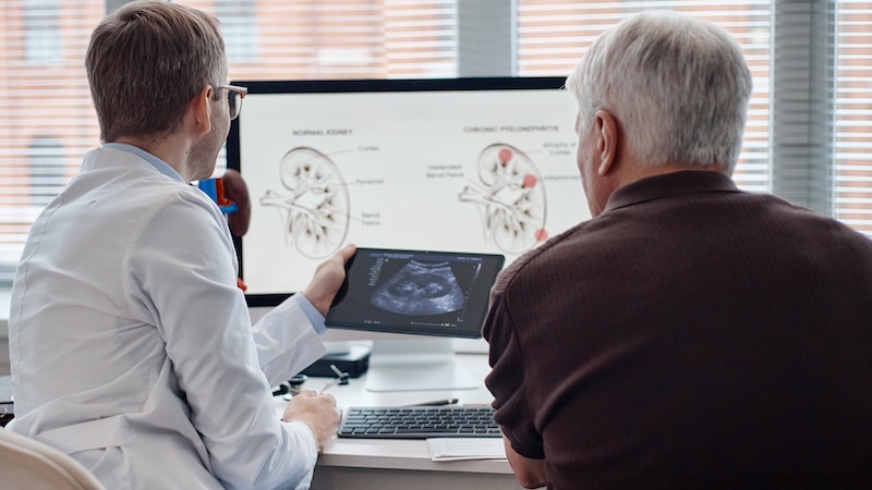 A man struggling with urinary incontinence looking at an x-ray with his doctor.
