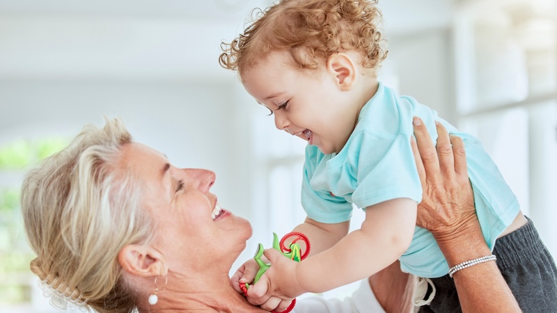 A woman lifting her young grandchild. Grip strength is an indicator of how well you are aging. Yuri Arcurs
