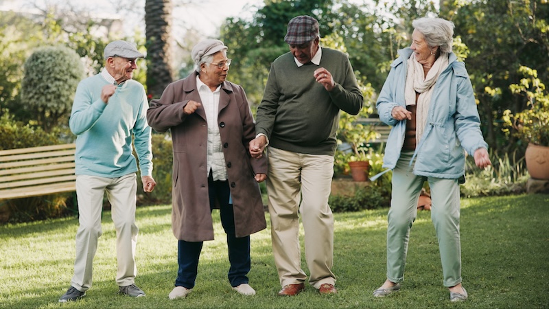 A group of retired people on a lawn, casually dancing. Reflecting trends in senior living. Yuri Arcurs