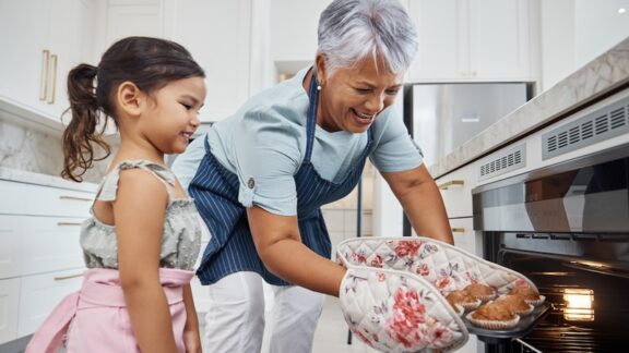 Granny au pair baking muffins with the young girl of the family.