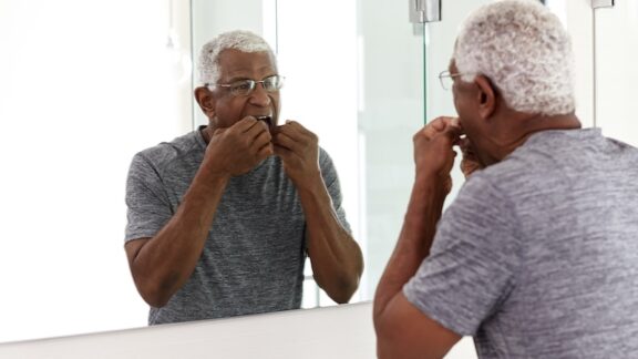 A black senior man flossing to prevent gum disease
