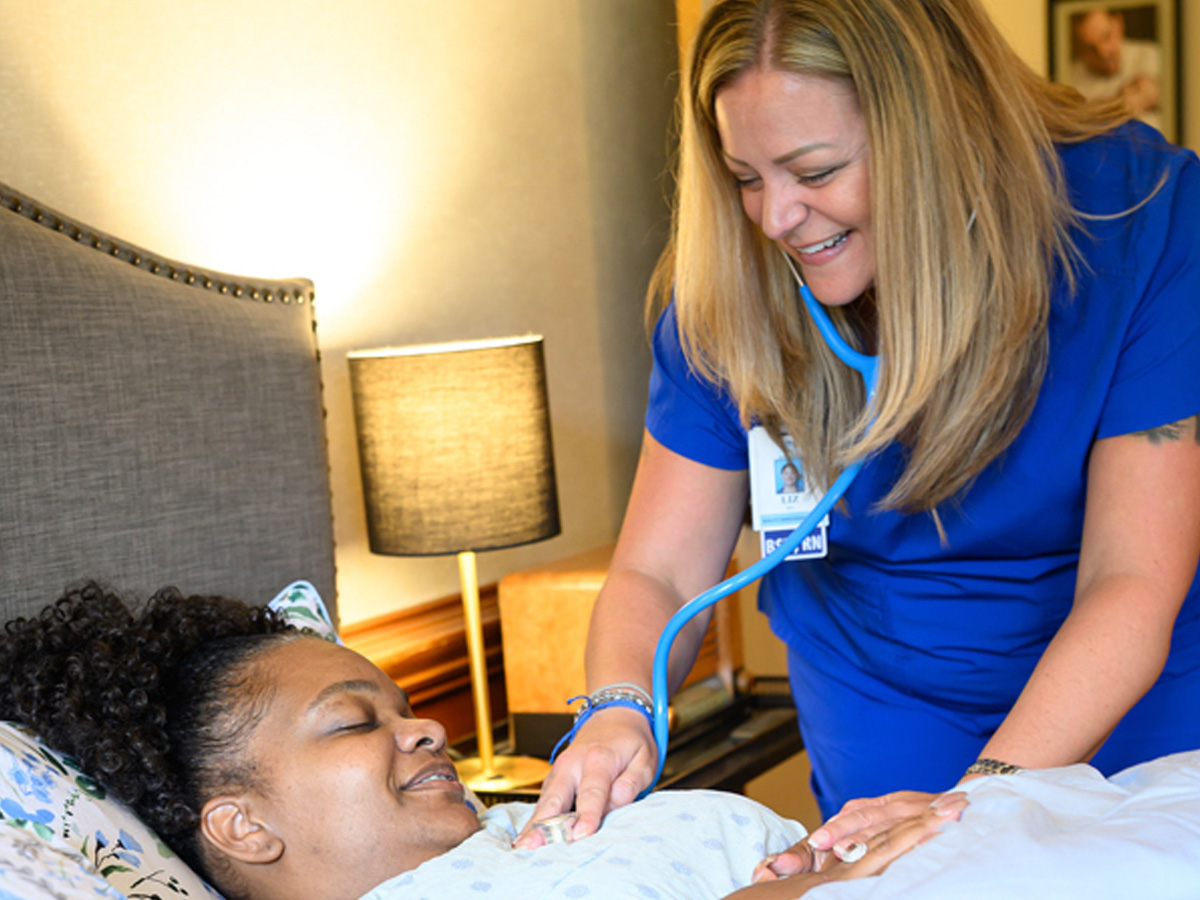 UNC Health Johnston Caregiver Helping Lady in Bed