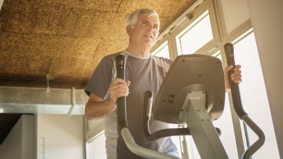 Senior man exercising on an elliptical and having fun doing it.