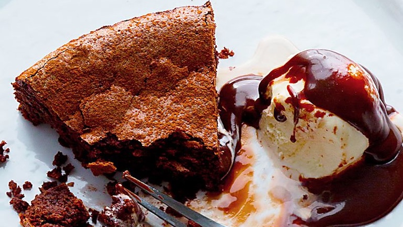 A slice of flourless chocolate cake next to ice cream.