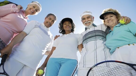 Senior friends together with tennis balls and racquets. Chances are, one of them suffers wrist pain from swing sports