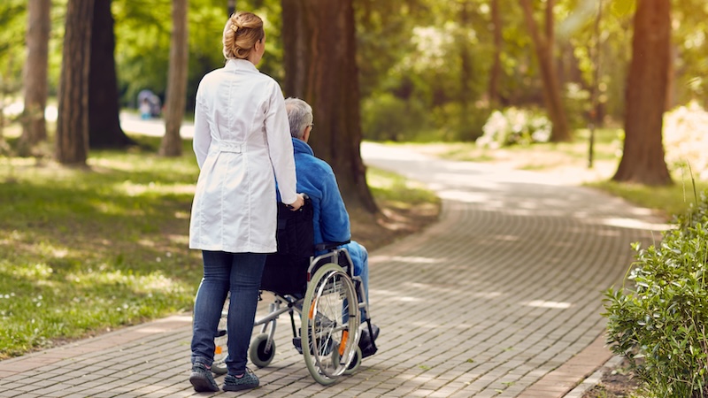 Planning for care is essential because of the likelihood of needing medical care in the future, like this senior being pushed down a sidewalk by a medical attendant. Image by Igor Mojzes.