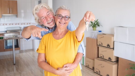 A senior couple in a new house with keys after they decided to move to a new state for retirement.