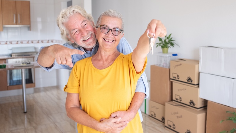 A senior couple in a new house with keys after they decided to move to a new state for retirement.