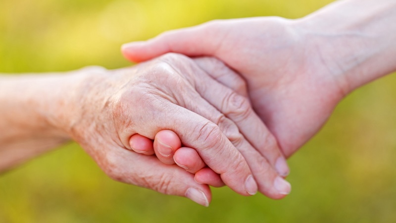 Younger and older hands holding each other. By Ocskay Bence. Concept of health care proxy and concern.