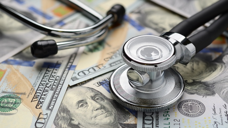 Dollars and a stethoscope, asking how to lower health care costs
