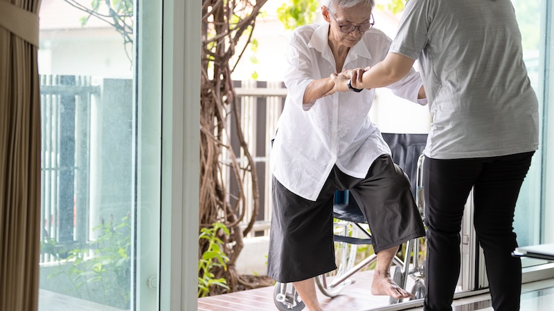 An elderly woman being helped by a caregiver.