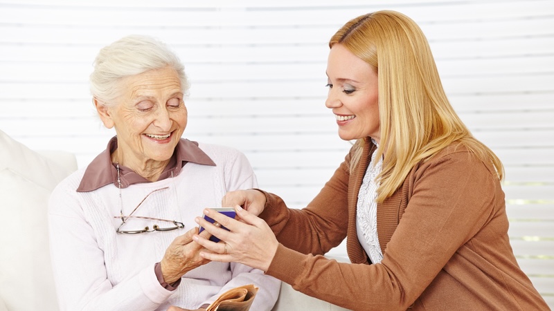 A young woman helping a senior woman use a smartphone - by Robert Kneschke. The best smartphones for seniors combine three key qualities: accessibility, user-friendliness, and security.