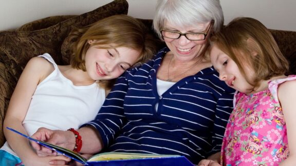A grandmother reading to two children, for essay on poetry collection, "Make a Circle, Keep Us In." Image Mathayward