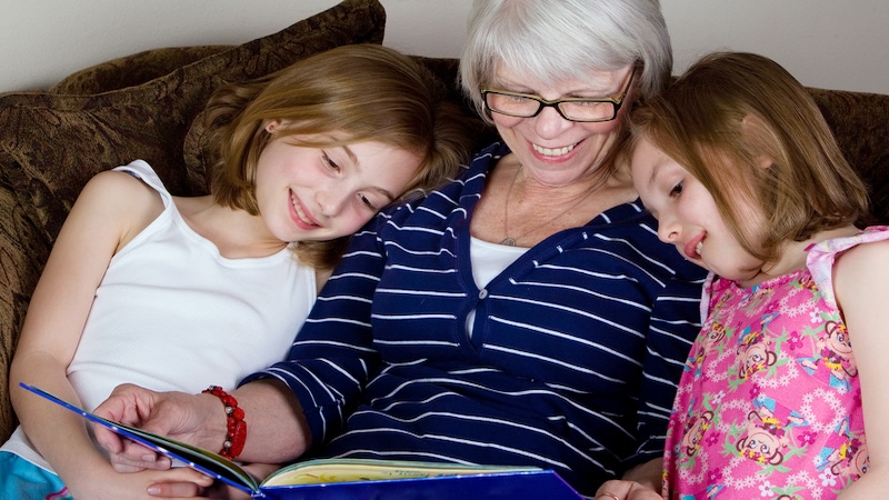 A grandmother reading to two children, for essay on poetry collection, "Make a Circle, Keep Us In." Image Mathayward