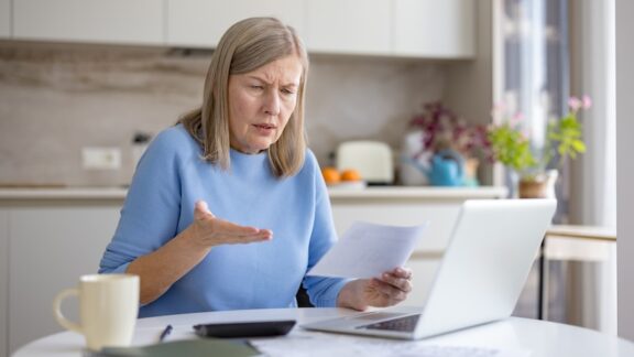 Woman looking at her computer in disbelief because of an insurance claim or preauthorization coverage denied.
