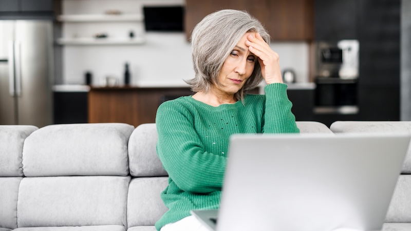 A woman unhappy at a computer because she claimed social security early.