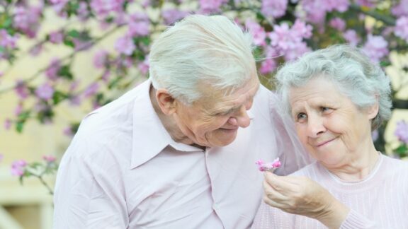 Happy older couple in front of a blooming tree. How Long Do You Want to Live? Halina Valiushka