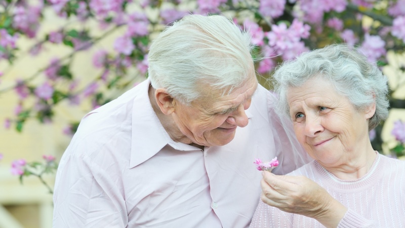 Happy older couple in front of a blooming tree. How Long Do You Want to Live? Halina Valiushka