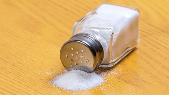 A salt shaker spilled on a table.