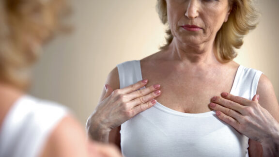 looking in mirror considering breast changes as women age. Motortion
