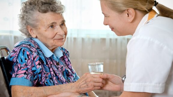 In choosing a memory care facility, you want to ensure that the people can care for your loved one. Here, a nurse aide gives a woman some water. Alexander Raths