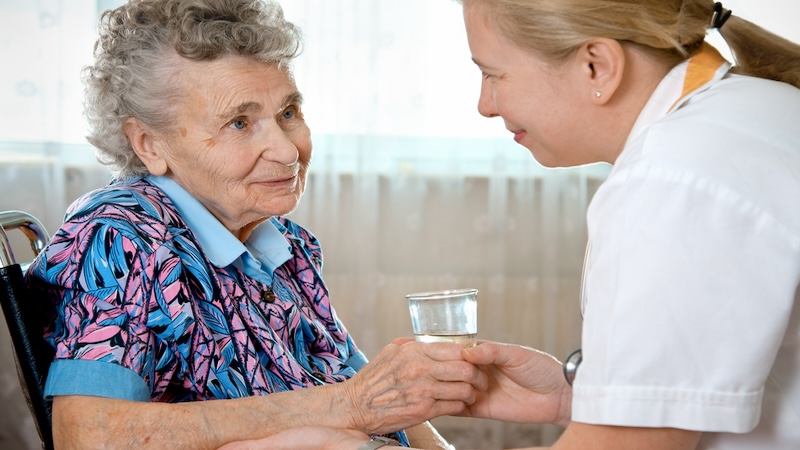 In choosing a memory care facility, you want to ensure that the people can care for your loved one. Here, a nurse aide gives a woman some water. Alexander Raths