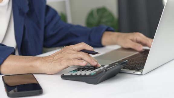 Someone in retirement crunching numbers on a computer. Figuring tax-breaks for self-employed retirees