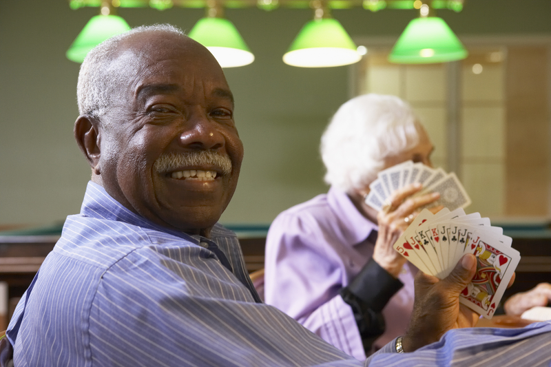 Men playing cards at an adult day care center. For article on senior living costs in Maryland. Monkey Business Images