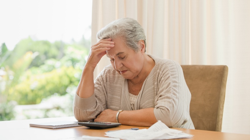 difficulties with finances can be a sign of dementia, as this woman stares dejectedly at her financial records